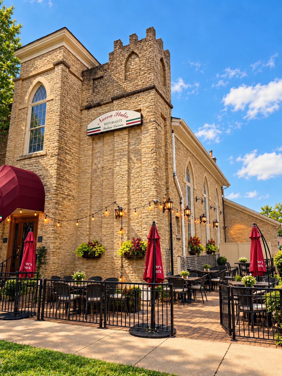 The stone exterior of Nuova Italia with a patio, red umbrellas and string lights